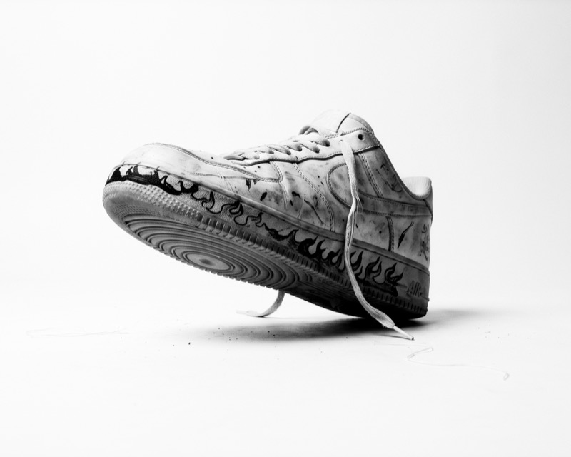 Worn white sneaker with hand-drawn flame artwork by Gabriette Schwaan