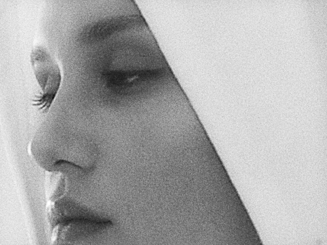 Black-and-white VHS still: close crop of a face in a hood